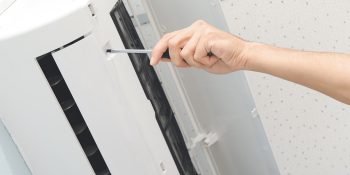Male Technician Repairing Air Conditioner Indoors