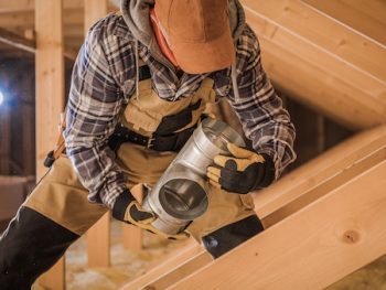 Male Contractor Assembling Hvac Pipes In Attic Of New House.